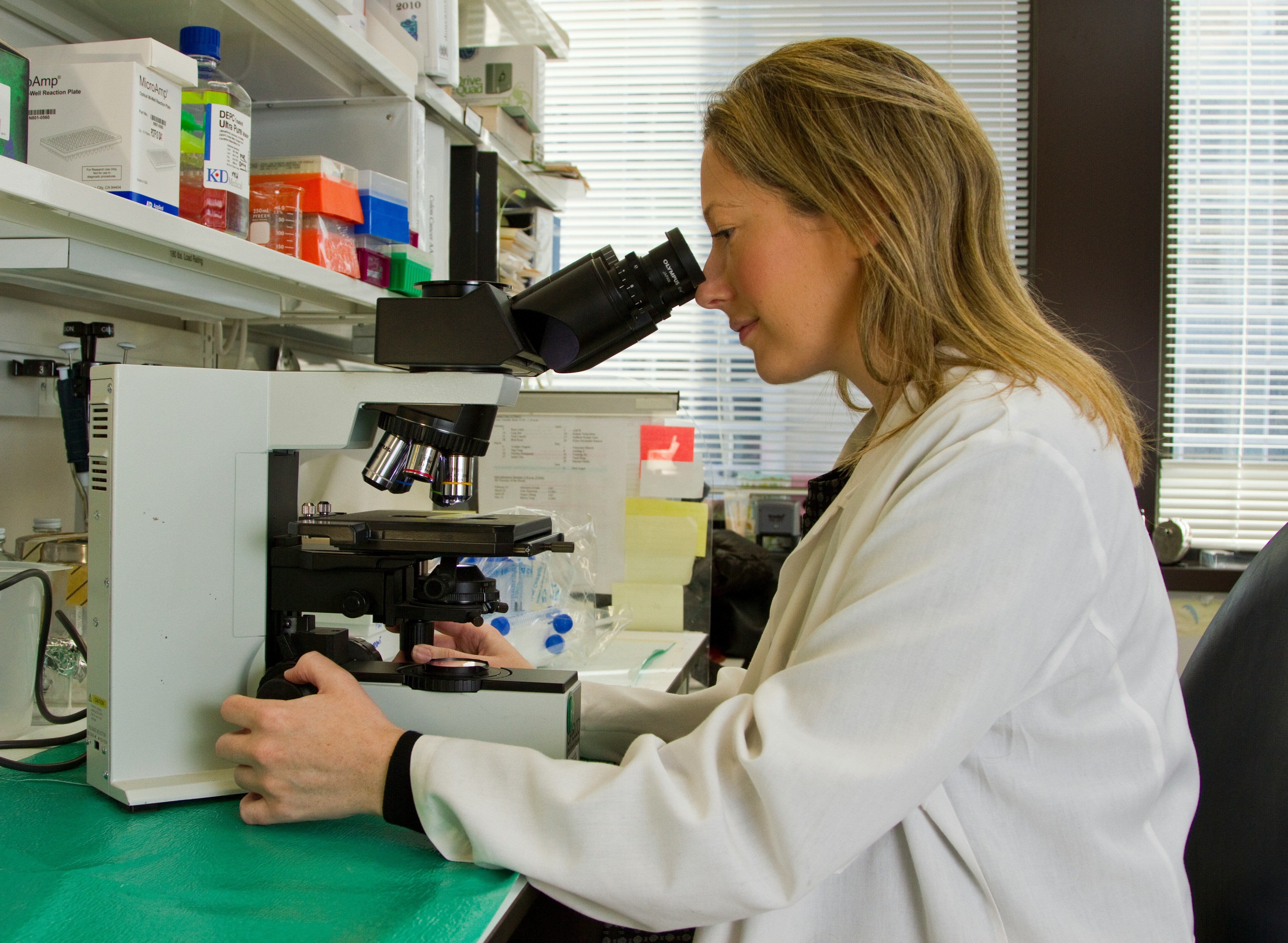 a blond female scientist sitting down experimenting